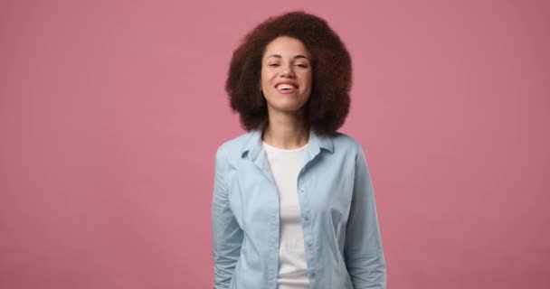 ハッピーフレンドリーな若いアフリカ系アメリカ人女性の波は ピンクの背景に立って肯定的な感情を表現もてなしの表情で誰かを歓迎します Dci 二重スローモーション — ストック動画