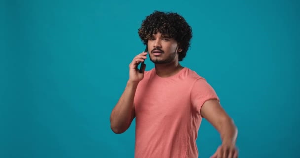 青いスタジオの背景に立っている電話に応答する電話で話す若い真剣な男 Dci 二重スローモーション — ストック動画