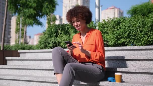Ung Afroamerikansk Kvinna Med Lockigt Hår Håller Smartphone Surfa Med — Stockvideo