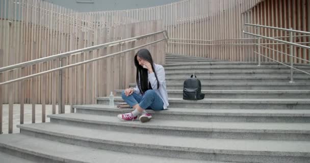 Gülümseyen Asyalı Genç Kız Öğrenci Merdivenlerde Oturuyor Cep Telefonuyla Konuşuyor — Stok video