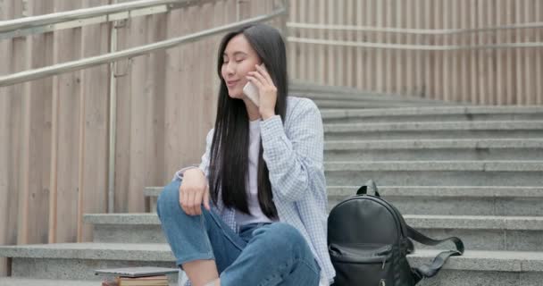 Χαμογελώντας Ασιατική Νεαρή Φοιτήτρια Γυναικείες Θέσεις Στις Σκάλες Και Μιλώντας — Αρχείο Βίντεο