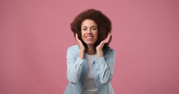 鏡を見てピンクの背景に立って髪に触れる魅力的なアフリカ系アメリカ人女性を笑顔 Dci 二重スローモーション — ストック動画