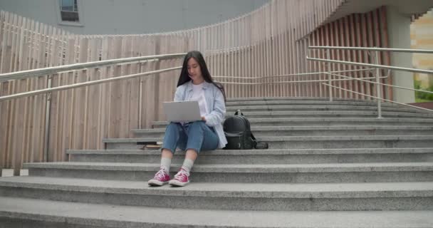 Genç Asyalı Kız Öğrenci Dışarıda Merdivenlerde Otururken Dizüstü Bilgisayar Kullanıyor — Stok video
