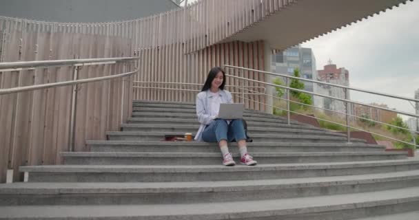 階段の屋外に座っている間 ラップトップを使用して若いアジアの女性学生 — ストック動画