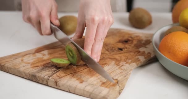 木製カッティングボードにナイフの新鮮な有機キウイでスライスした女性 Dciについて スローモーション — ストック動画