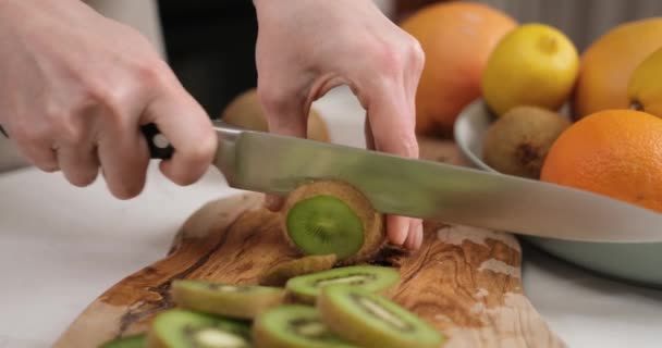 木製カッティングボードにナイフの新鮮な有機キウイでスライスした女性 Dciについて スローモーション — ストック動画