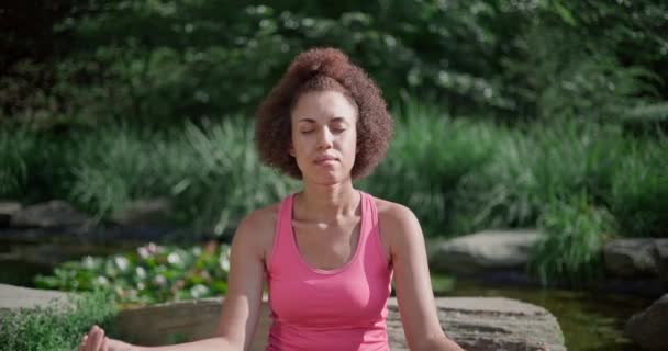 Νεαρή Αφροαμερικανή Κάθεται Στάση Λωτού Μάτια Και Διαλογίζεται Κάνοντας Γιόγκα — Αρχείο Βίντεο