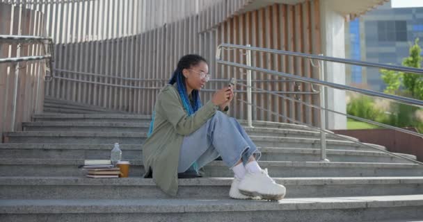 Joven Afroamericana Americana Estudiante Escribiendo Mensaje Escritura Teléfono Móvil Mientras — Vídeos de Stock