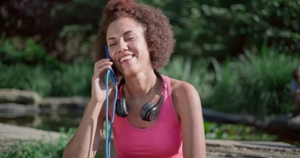 Νεαρή Αφροαμερικανίδα Γυναίκα Ακούει Μουσική Και Κοιτάζει Τηλέφωνο Κάθεται Στο — Αρχείο Βίντεο