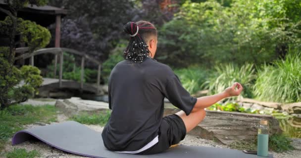 年轻的非洲裔美国精神人士坐在公园的室外背景下沉思瑜伽 — 图库视频影像