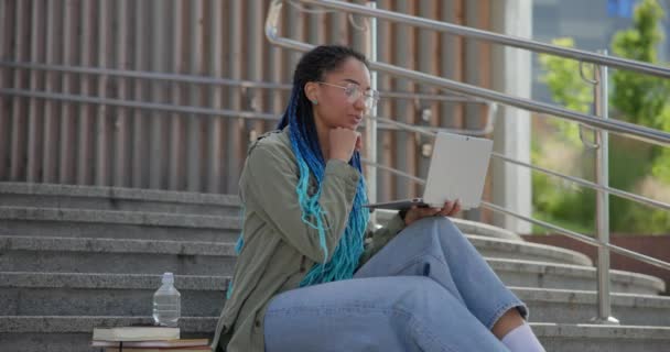 年轻的非洲裔美国女学生或自由职业者坐在室外用手提电脑打视频电话 — 图库视频影像