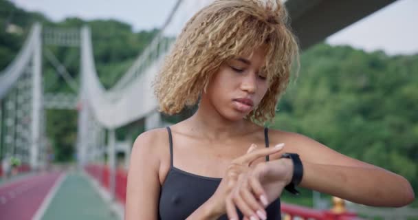 Спортивная Африканская Американка Смотрит Свой Спортивный Браслет Рукой Проверяя Данные — стоковое видео