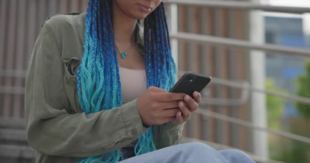 年轻的非洲裔美国女学生坐在户外台阶上 一边用手机打字一边写信息 — 图库视频影像