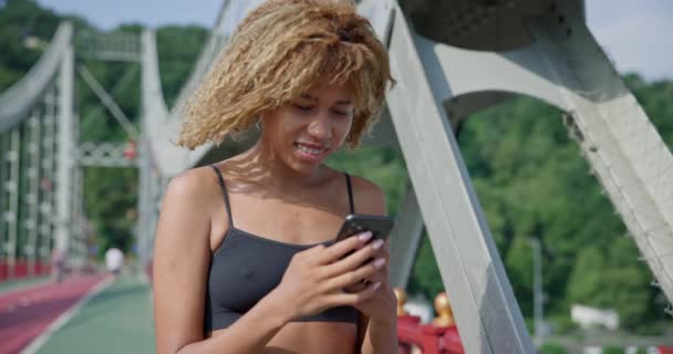 Giovane Donna Sportiva Afroamericana Utilizzando Smartphone Piedi All Aperto Ponte — Video Stock