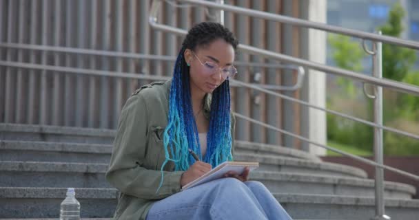 Genç Afrikalı Amerikalı Kadın Öğrenci Dışarıda Merdivenlerde Otururken Deftere Notlar — Stok video