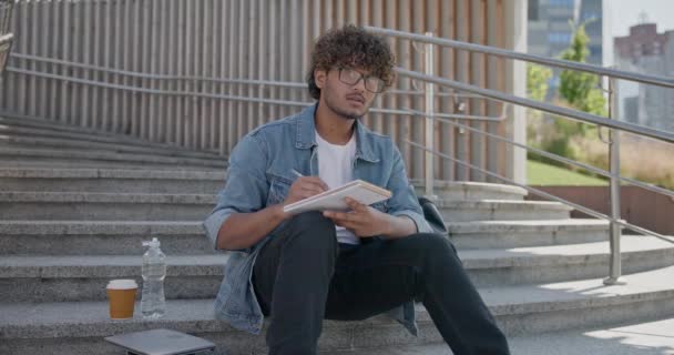 Jovem Estudante Indiano Fazendo Anotações Caderno Enquanto Estava Sentado Uma — Vídeo de Stock