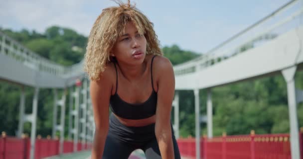 若いアフリカ系アメリカ人女性が屋外の橋でジョギングした後疲れ果てた — ストック動画