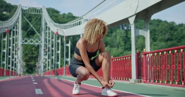 Muda African American Wanita Mengikat Sepatu Olahraga Duduk Jembatan Kota — Stok Video