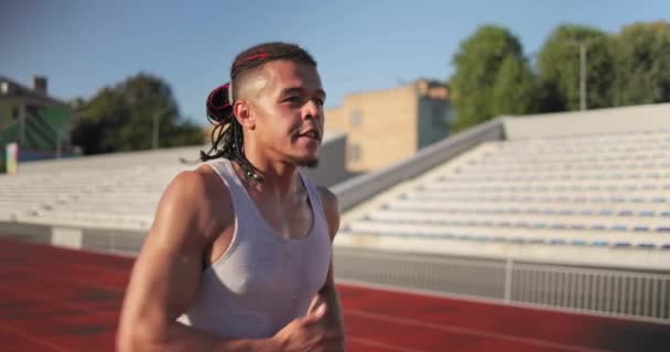 アフリカ系アメリカ人のランナー選手がスタジアムでジョギングをする スローモーション — ストック動画