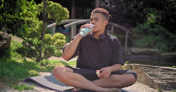 Genç Afro Amerikan Maneviyatı Adamı Yoga Yapıyor Parkta Oturmuş Içiyor — Stok video