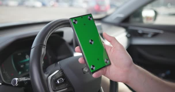男は駐車場の車に座り 緑色のスクリーンでスマートフォンを保持しています Dciについて — ストック動画