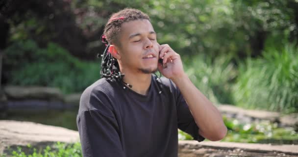 若いアフリカ系アメリカ人のスピリチュアリティマンは 公園の屋外に座って電話で話すヨガアサナ瞑想 — ストック動画