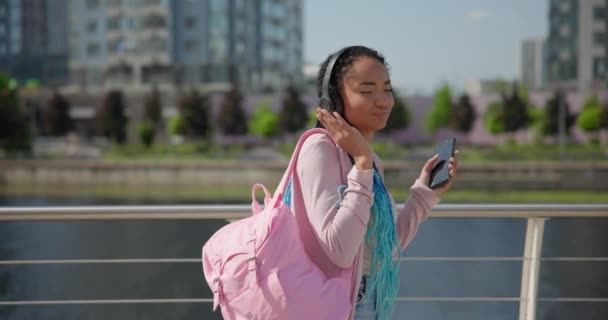 年轻的非洲裔美国女人 带着恐惧的头发行走和探索城市 聆听音乐 — 图库视频影像