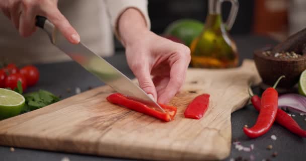 Mulher Cortando Pimenta Vermelha Quente Uma Tábua Corte Madeira Cozinha — Vídeo de Stock