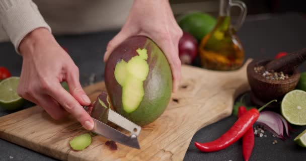 家庭用キッチンで木製カッティングボードにマンゴーを剥いだ女性 Dciについて — ストック動画