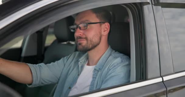 Νεαρός Καυκάσιος Κάθεται Ένα Αυτοκίνητο Ένα Πάρκινγκ Και Κοιτάζει Την — Αρχείο Βίντεο