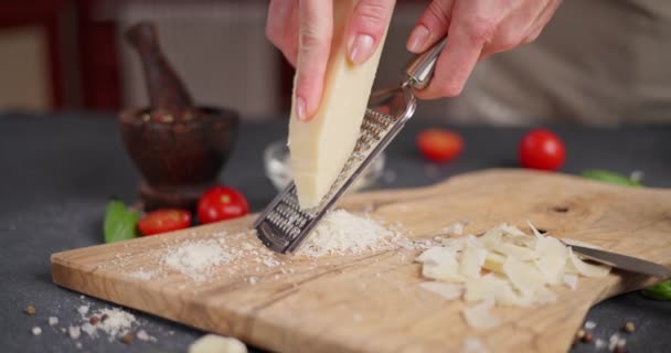 女性は 伝統的なイタリアのパルメザンハードチーズのピースを国内のキッチンで木製の切断ボードに格子を与えています Dciについて — ストック動画