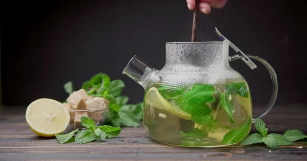 将天然的有机草本茶与柠檬和薄荷混合在玻璃杯茶壶中 配上木勺 — 图库视频影像