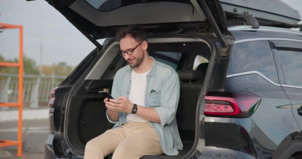 Mladý Běloch Sedí Podlaze Kufru Auta Používá Smartphone Dci — Stock video
