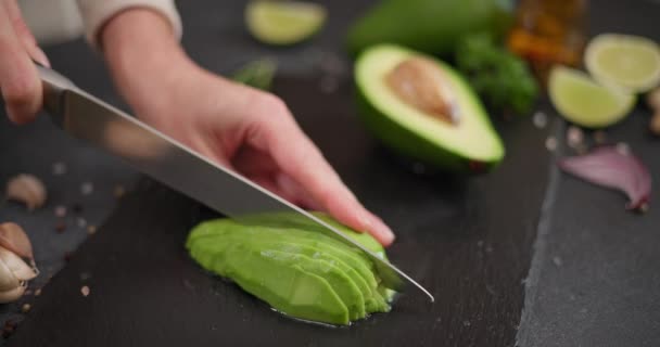 女人用刀把新鲜的绿色鳄梨水果切在石板上 放在桌子上 Dci — 图库视频影像