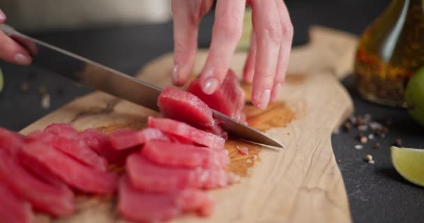 女性は国内のキッチンで木製の切断板のスライスにマグロのステーキを切りました Dciについて — ストック動画