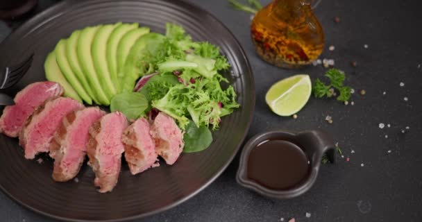 Grillezett Tonhal Steak Szeletelt Avokádóval Egy Fekete Tálalóasztalon Teriyaki Szósszal — Stock videók