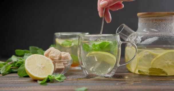 将柠檬片与天然的有机草本植物茶一起放在木制桌子上的玻璃壶中 — 图库视频影像