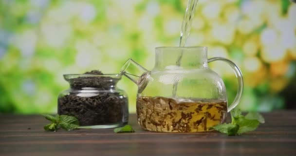 热开水倒入玻璃杯茶壶 在木桌上放上红茶叶 — 图库视频影像