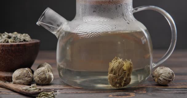 花茶花球在木制背景热开水的玻璃杯茶壶中酝酿的时间 — 图库视频影像