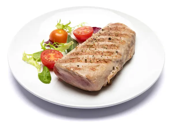 grilled cooked piece of tuna fillet on ceramic plate isolated on white background.