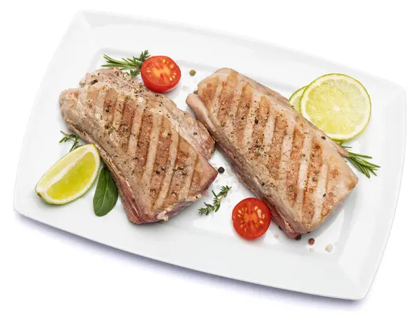 grilled cooked piece of tuna fillet on ceramic plate isolated on white background.