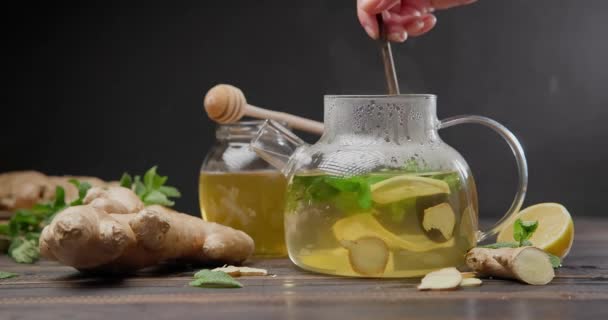 妇女将新鲜酿制的有机草本茶与生姜 薄荷和柠檬混合在玻璃杯茶壶中 — 图库视频影像