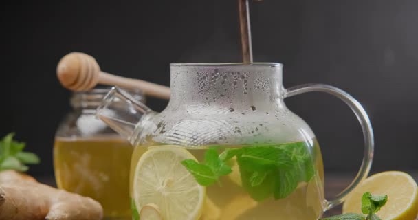 妇女将新鲜酿制的有机草本茶与生姜 薄荷和柠檬混合在玻璃杯茶壶中 — 图库视频影像