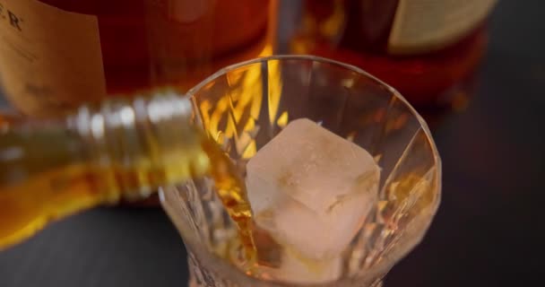 Barmen Şişelerin Arka Planında Soğutmak Için Buzlu Bardağa Viski Doldurur — Stok video