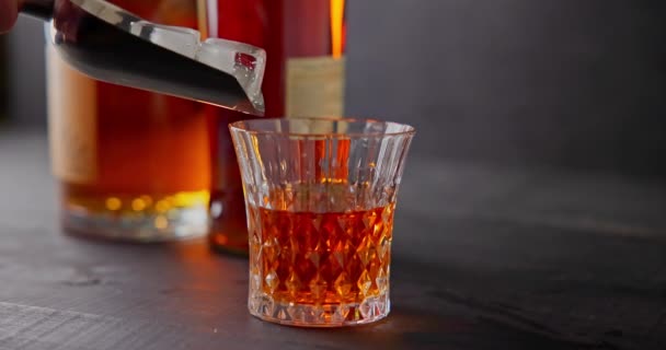 Bartendern Lägger Isbitar För Kylning Ett Glas Whisky Bakgrund Flaskor — Stockvideo