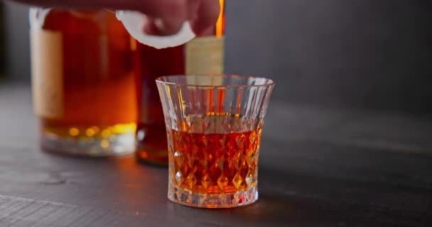 バーテンダーは ボトルの背景にウイスキーのガラスに冷却するための氷球を置きます Dci スローモーション映像 動画クリップ