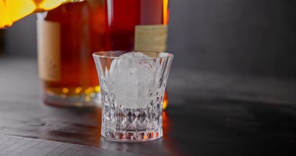 Barkeeper Gießt Whiskey Glas Mit Eis Zum Abkühlen Auf Einem — Stockvideo