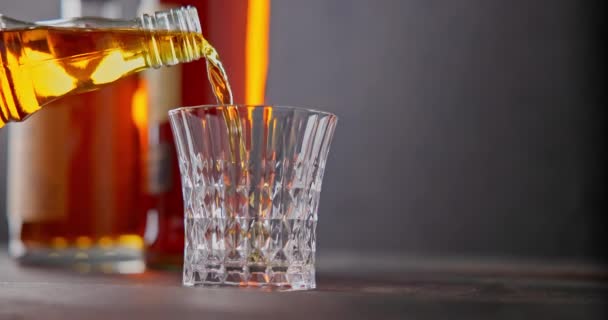 バーテンダーは ボトルの背景に対してガラスゴブレットにウイスキーをプールします Dci スローモーションビデオ — ストック動画