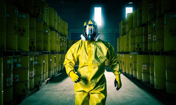 Man in mask and yellow protective clothing walks inside a slag storage site.