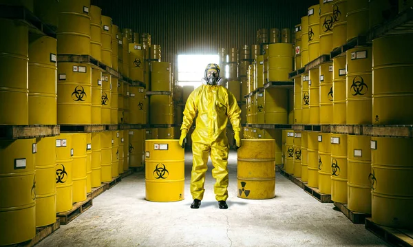 storage of metal barrels toxic waste and man in yellow protective suit